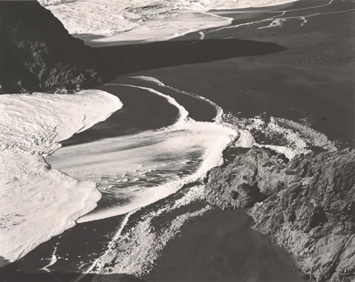 Edward Weston Fotografía en blanco y negro de Edward Weston titulada “Surf, Bodega” (1937), presente en la exposición La Materia de las Formas de Fundación MAPFRE. La imagen, de temática marítima, capta la fuerza y el movimiento dinámico de las olas rompiendo en la costa rocosa.