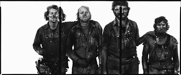 Richard Avedon Retrato en blanco y negro de cuatro trabajadores con la ropa y el rostro manchados, de pie frente a un fondo blanco, perteneciente a la serie In the American West de Richard Avedon.