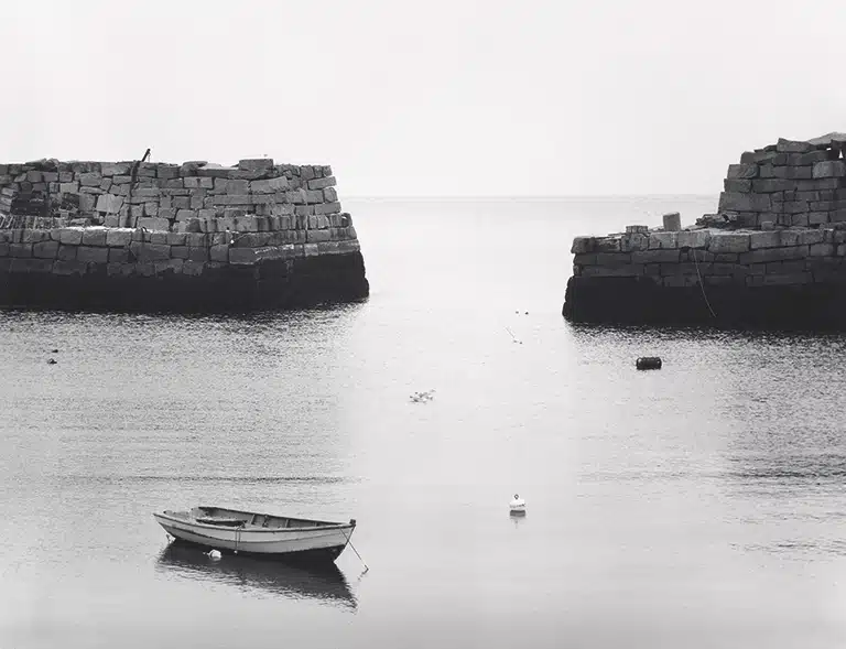 Minor White Barca en aguas tranquilas entre muros de piedra en blanco y negro